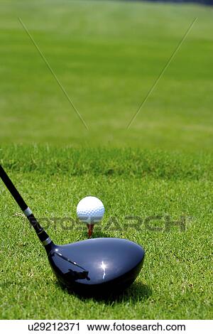 Stock Image - Golf club by ball on tee, close-up. Fotosearch