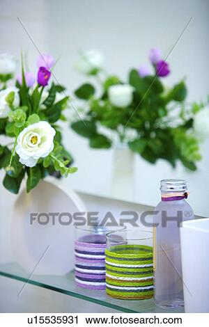 Stock Image - Flowers, mugs and bottle in bathroom. Fotosearch