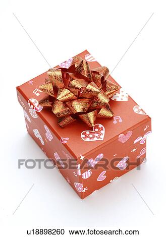 Stock Image - Gift with flower shaped red ribbon, close-up. Fotosearch