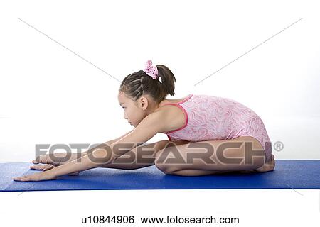 Stock Photograph - Girl practicing gymnastic pose on pad, side view. Fotosearch