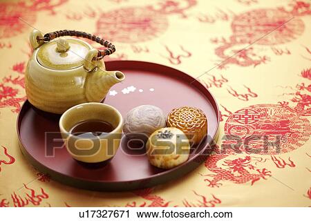 Stock Image - Egg york pastry, mooncake, a cup of tea and teapot. Fotosearch