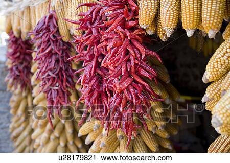 Stock Image - Chili peppers and corns hanging out to dry. Fotosearch