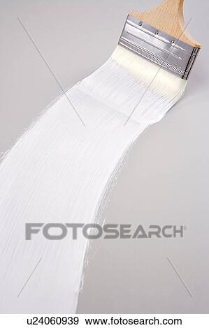 Stock Photo - Paintbrush and white paint on canvas, close-up. Fotosearch