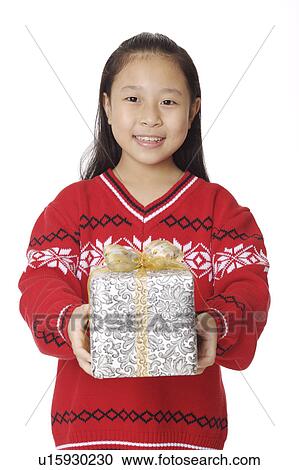 Stock Image - Girl holding a wrapped gift and smiling at the camera. Fotosearch