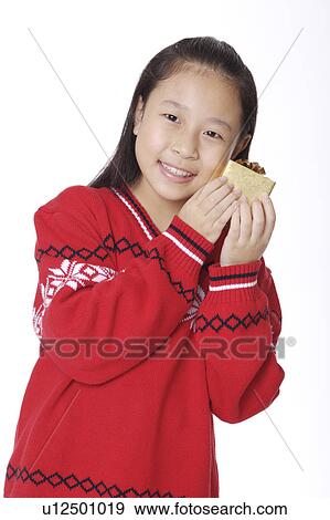 Stock Photo - Girl holding a wrapped gift and smiling at the camera. Fotosearch