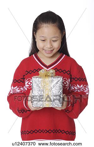 Stock Image - Little girl holding wrapped gift and smiling. Fotosearch