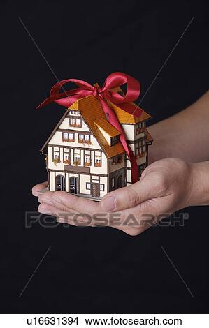 Picture - Man's hand holding a house model as a gift. Fotosearch