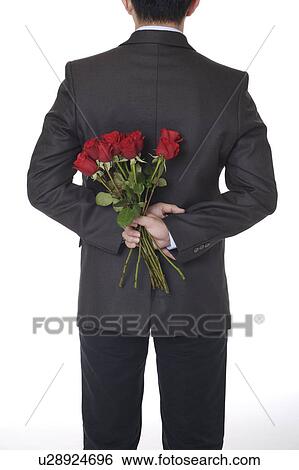 Stock Photograph - Man's hands holding a bouquet of red roses behind back. Fotosearch