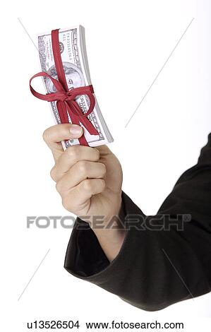 Picture - One hand holding a stack of paper money with red bowknot. Fotosearch