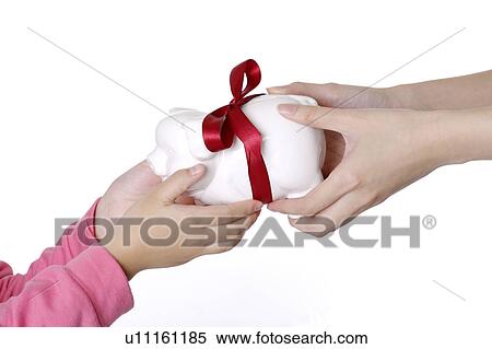 Stock Photography - Woman giving a piggy bank to little girl as a gift. Fotosearch