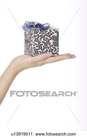 Stock Image - Woman's hand holding a wrapped gift. Fotosearch
