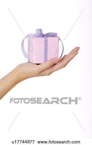 Stock Photo - Woman's hand holding a wrapped gift with beautiful packaging. Fotosearch