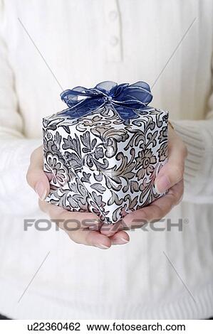 Stock Image - Woman's hands holding a wrapped gift with beautiful packaging. Fotosearch