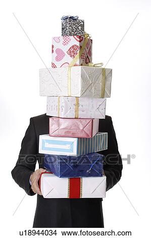 Picture - Young man holding a stack of wrapped gifts. Fotosearch