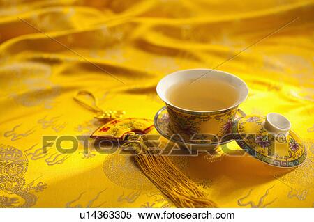 Stock Photography - Close-up of a cup of tea and Chinese decoration on textile with lucky pattern. Fotosearch