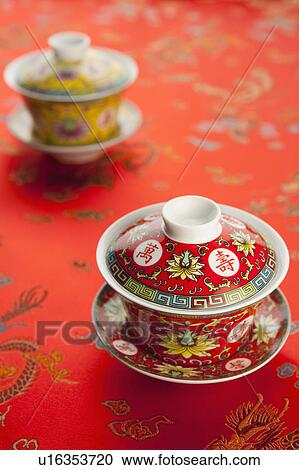 Stock Image - Close-up of two teacups on red textile with lucky pattern. Fotosearch