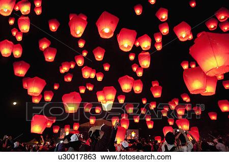 Stock Image - Illuminated sky lanterns flying into sky at night. Fotosearch