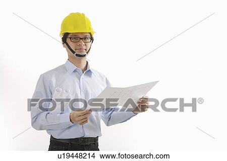 Picture - Engineer holding blueprint and looking at the camera. Fotosearch