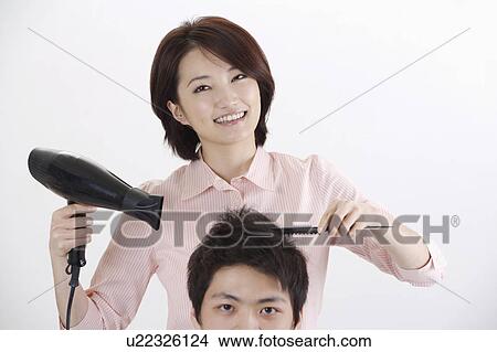 Picture - Female hairdresser drying hair for young man. Fotosearch