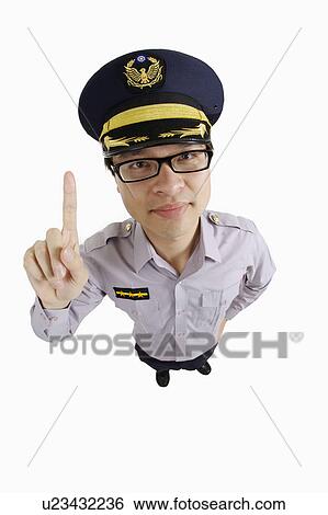 Stock Photograph - Male police officer looking at the camera with one finger up. Fotosearch