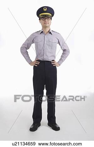 Stock Photo - Male police officer standing with arms akimbo. Fotosearch