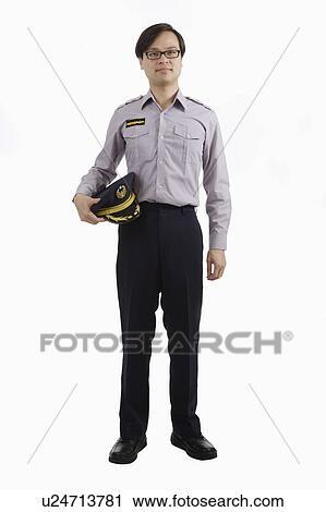 Stock Image - Police officer standing and holding uniform cap. Fotosearch