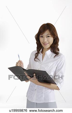 Stock Photograph - Young female journalist holding clipboard and writing. Fotosearch