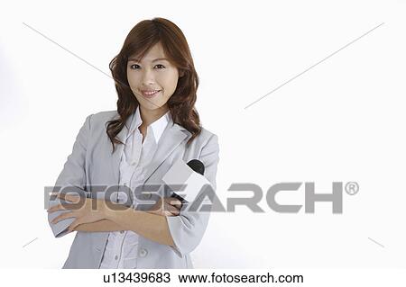 Stock Image - Young female journalist standing with hands on chest. Fotosearch