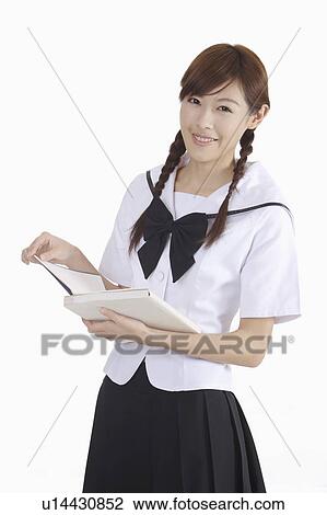 Stock Image - "Young female student holding a book and smiling, portrait". Fotosearch
