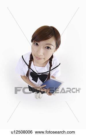 Stock Photograph - Young female student holding books and looking at the camera. Fotosearch