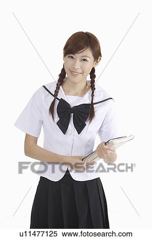 Stock Photography - "Young female student holding books and smiling at the camera, portrait". Fotosearch