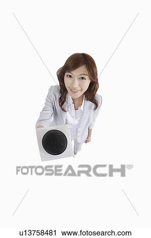 Stock Image - Young female TV reporter holding microphone and looking at the camera. Fotosearch