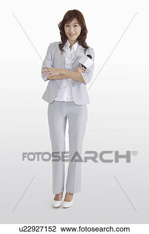 Stock Image - Young female TV reporter standing with hands on chest. Fotosearch