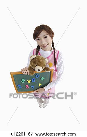 Young teacher of kindergarten holding a little blackboard and teddy bear View Large Photo Image Stock Photo - Young teacher of kindergarten holding a little blackboard and teddy bear. Fotosearch