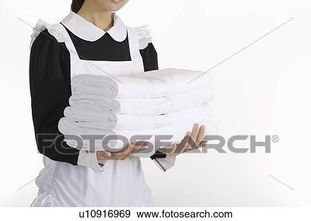 Stock Photo - Young waitress holding a stack of towels. Fotosearch