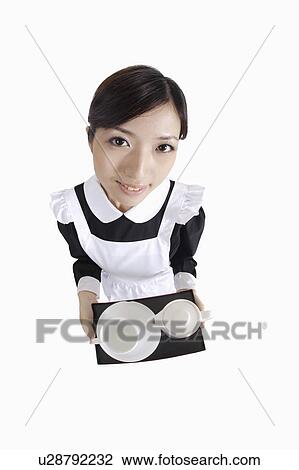 Young waitress holding a tray and looking at the camera View Large Photo Image Stock Image - Young waitress holding a tray and looking at the camera. Fotosearch