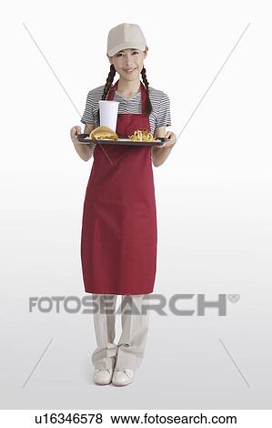 Stock Photo - Young waitress holding a tray with fast food. Fotosearch
