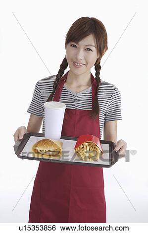 Stock Photograph - Young waitress holding a tray with fast food. Fotosearch