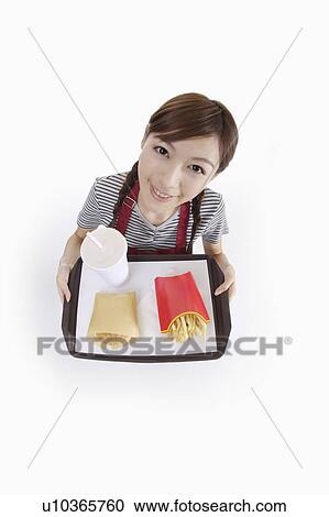 Stock Image - Young waitress holding fast food on the tray. Fotosearch