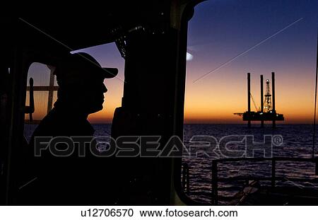 Stock Image - Boat Captain's View Offshore Oil Drilling Rig at Sunset. Fotosearch