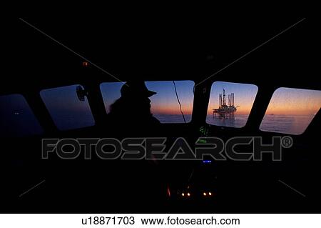 Stock Image - Boat Captain's View Offshore Oil Drilling Rig at Sunset. Fotosearch