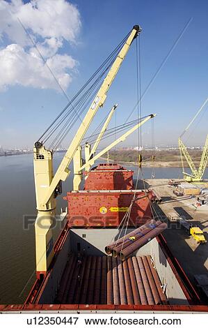 Stock Photo - Crane Offloading Pipe from Cargo Ship. Fotosearch