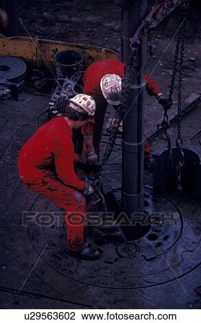 Stock Image - Drilling Rig Worker Setting Slips on Drill Pipe. Fotosearch