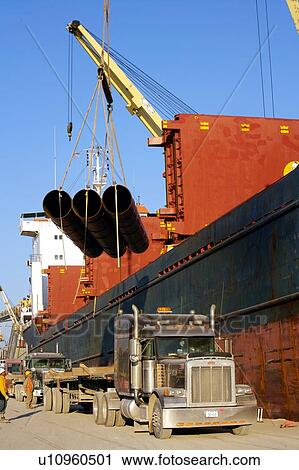 Stock Image - Offloading Pipe from Cargo Ship to Truck. Fotosearch