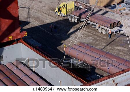 Stock Photo - Offloading Pipe from Cargo Ship to Truck. Fotosearch