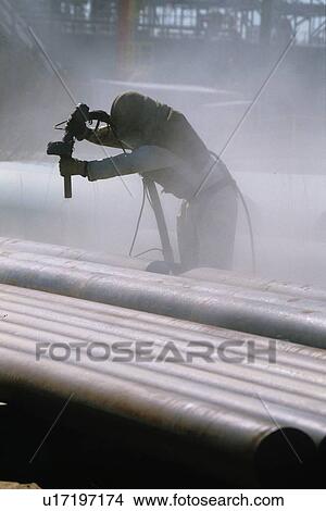 Picture - Oil Facility Worker Cleaning Pipe. Fotosearch