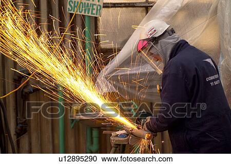 Stock Image - Oil Refinery Worker Grinding Pipe. Fotosearch