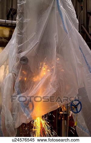 Stock Photography - Oil Refinery Worker Grinding Pipe with Plastic Sheeting Cover. Fotosearch