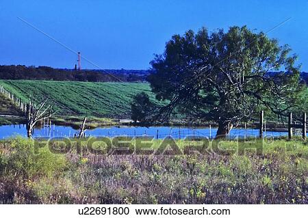 Onshore Oil Drilling Rig in Farmland with Pond and Tree in Foreground View Large Photo Image Stock Image - Onshore Oil Drilling Rig in Farmland with Pond and Tree in Foreground. Fotosearch