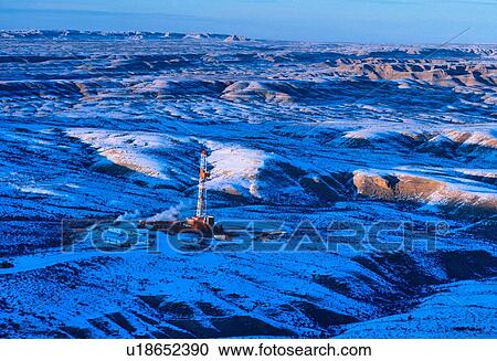Stock Image - Onshore Oil Drilling Rig in Mountainous Snow Covered Terrain. Fotosearch